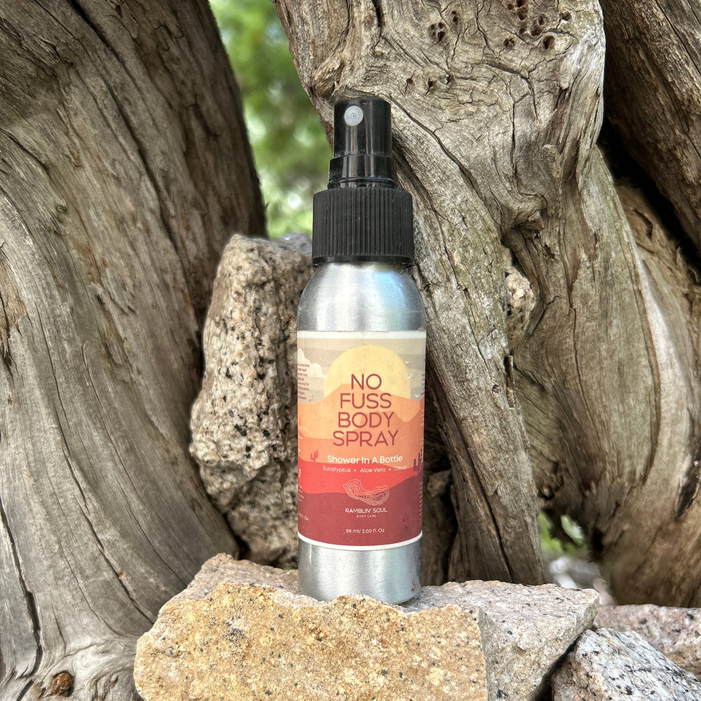Body spray bottle labeled 'No Fuss Body Spray' on a natural stone background