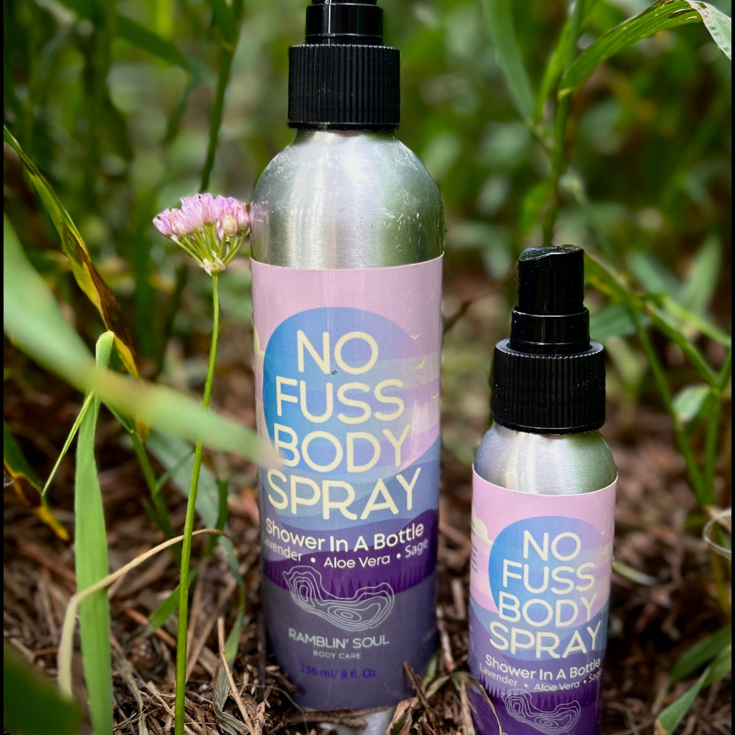 Two 'No Fuss Body Spray' bottles in a grassy area