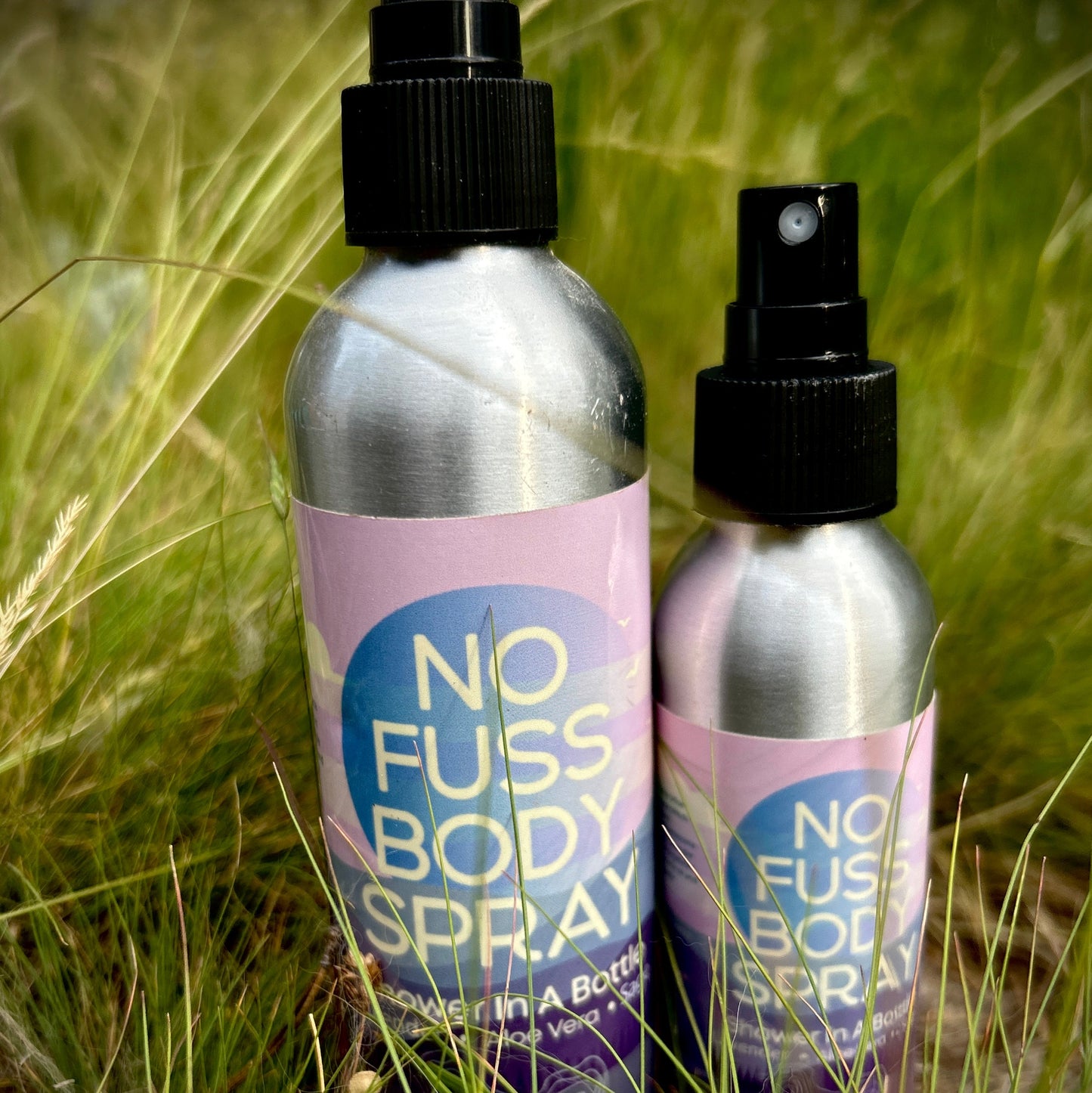 Two bottles of 'No Fuss Body Spray' in a grassy outdoor setting