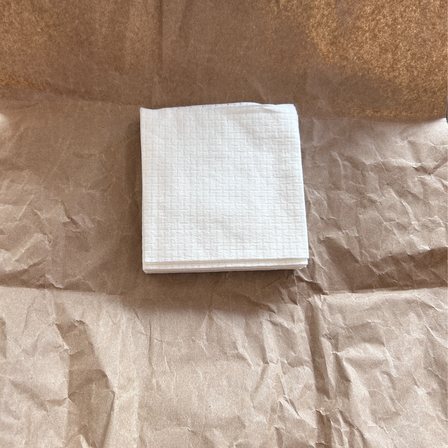 A white square cloth on a brown kraft paper surface.